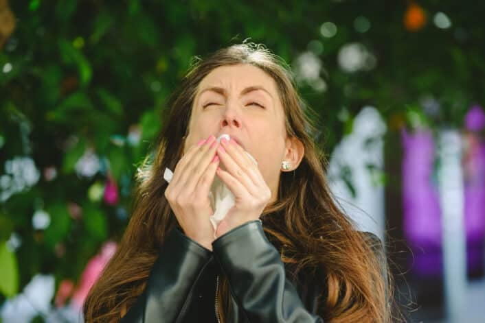 Woman sneezing in the daylight, illustrating the genetic cause behind the photic sneeze reflex