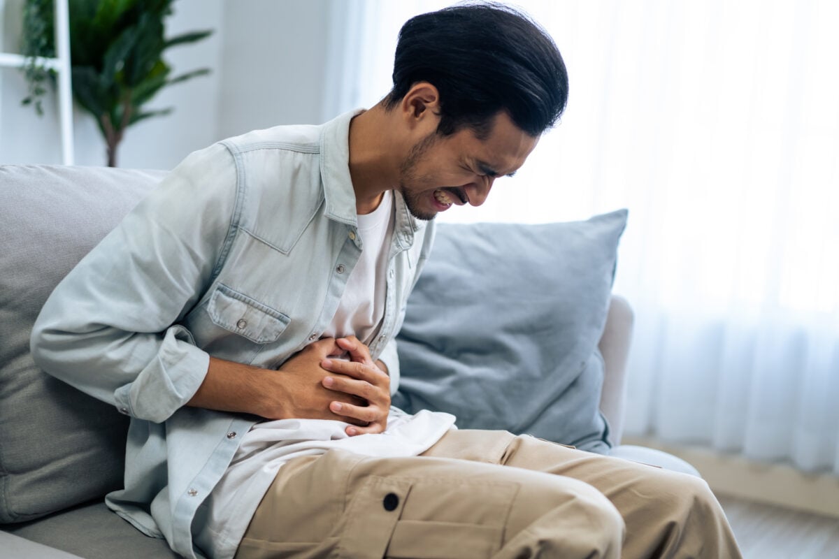 Man holding his stomach in pain, depicting the discomfort caused by diverticulosis.