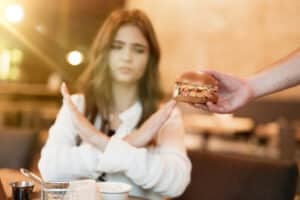 A woman saying no to a burger, highlighting how lifestyle choices may influence blast count and immune health.