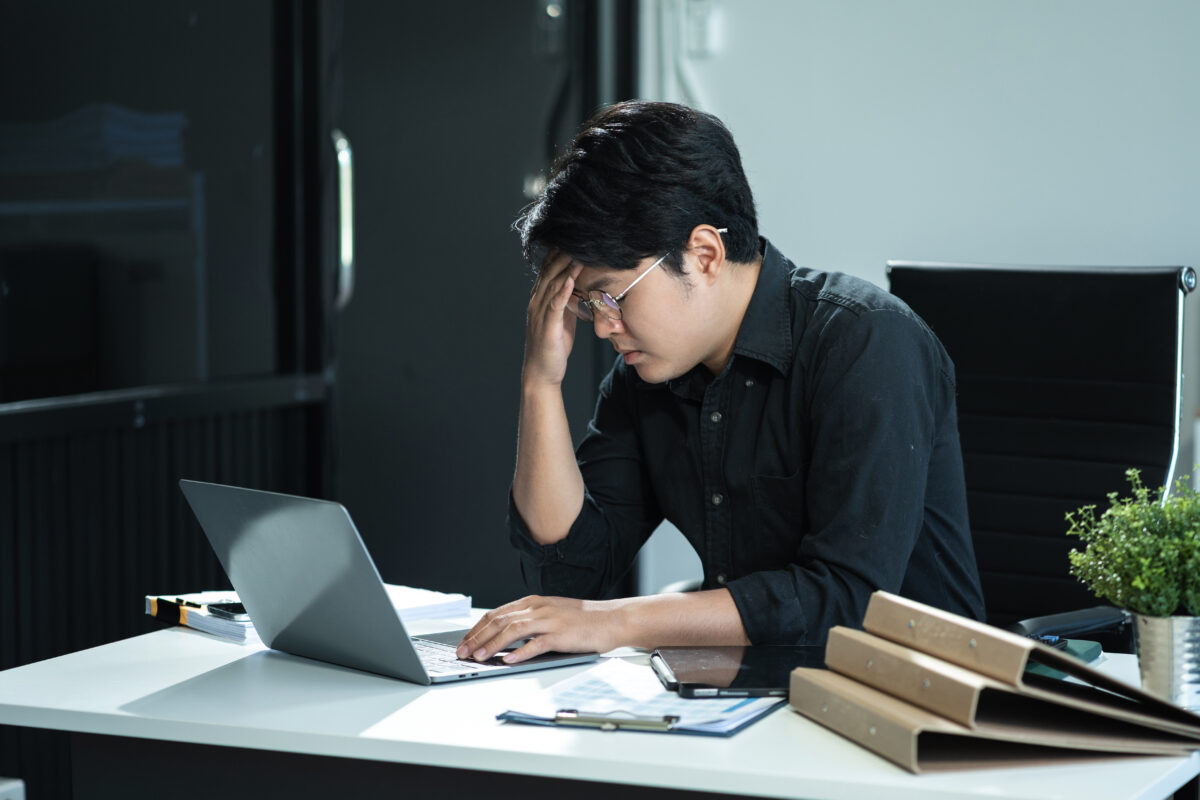 A man looks down tired at his desk, symbolizing the physical and emotional toll of living with hereditary amyloidosis.