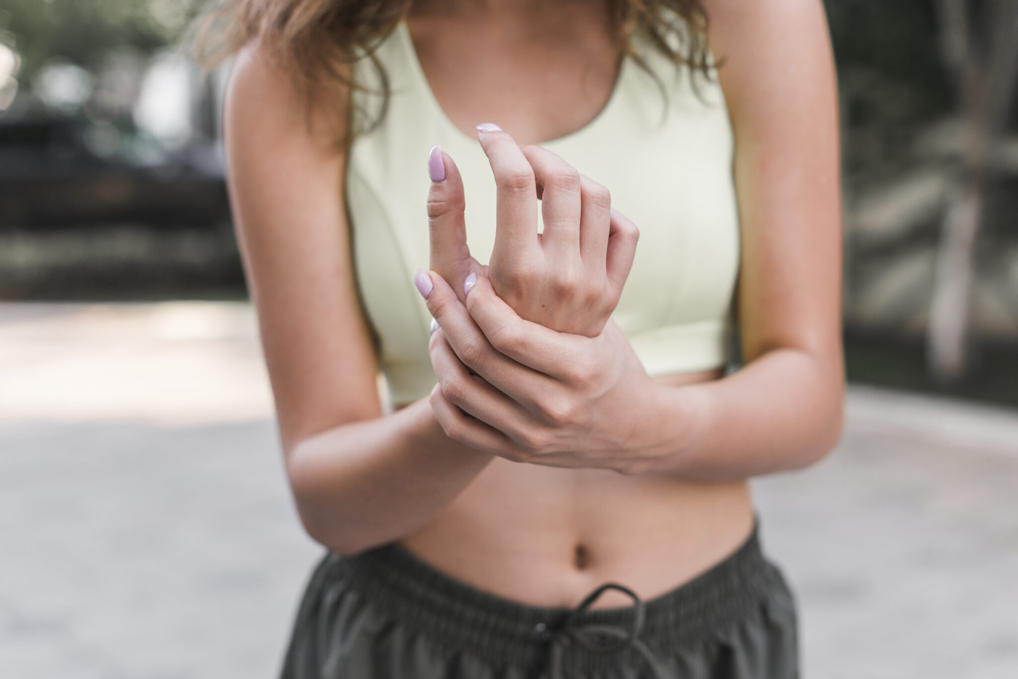 A woman holding her hands, checking for pain, illustrating the impact of mucolipidosis on physical health