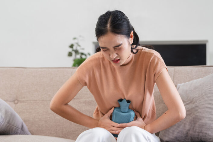 Woman in pain, possibly from bladder discomfort, representing the symptoms and health effects of uterine fibroids