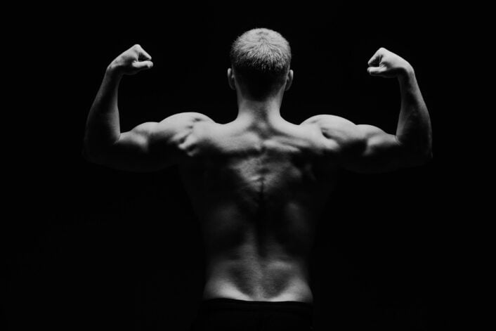 Black and white image of a muscular man, symbolizing the connection between muscle health and aspartate aminotransferase (AST) levels