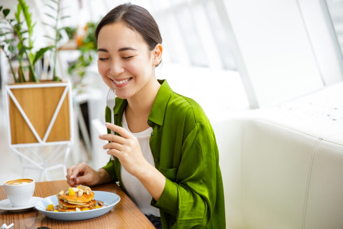 A woman smiling and eating, symbolizing the positive effects of GLP-1 medication on health and well-being