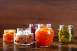 An image of assortment of fermented and probiotic foods, including canned vegetables or pickles which may trigger symptoms in individuals with histamine intolerance.