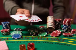 image of a hand playing cards at a gambling table, representing the possible genetic link to gambling behavior