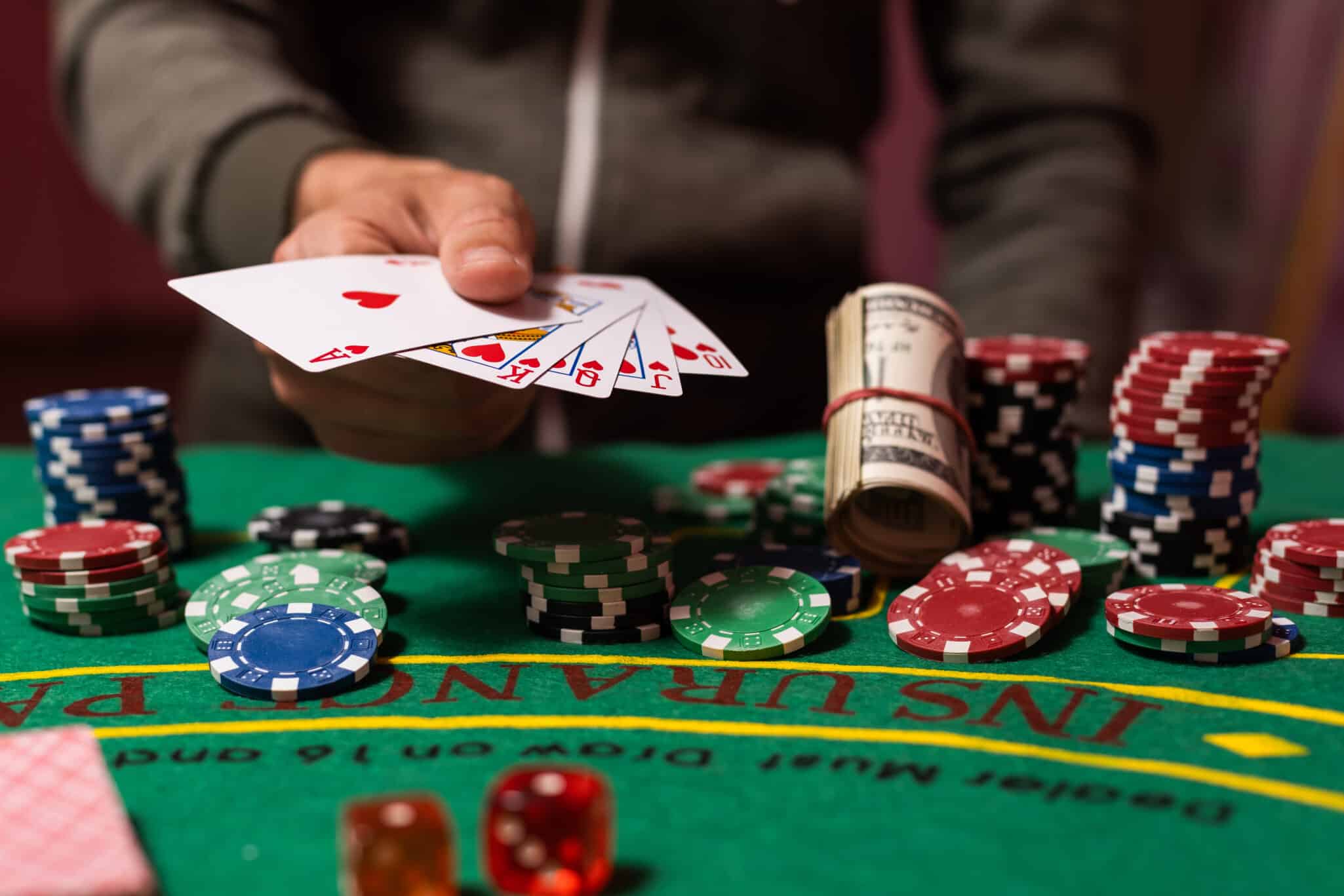 image of a hand playing cards at a gambling table, representing the possible genetic link to gambling behavior