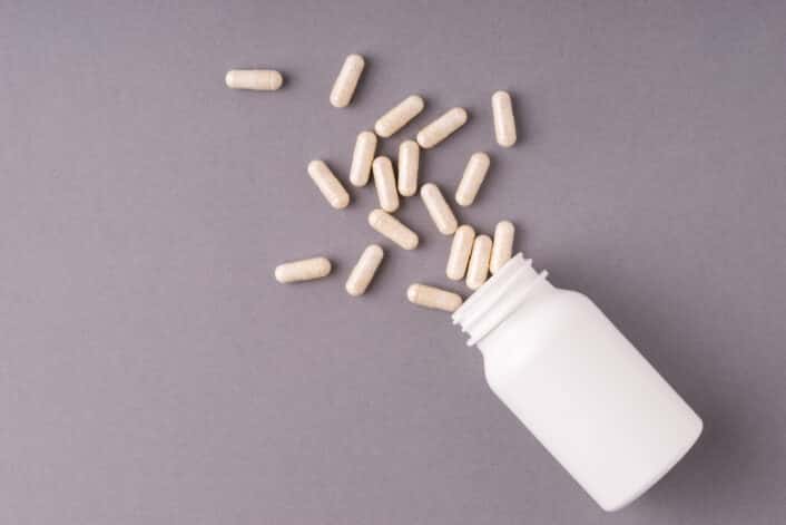 This image features a set of white lithium orotate supplement pills alongside a DNA model, emphasizing the connection between genetics and individual response to the compound.