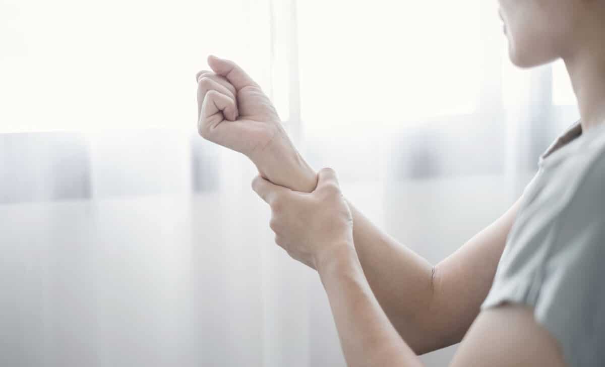 Woman holding her arm due to muscle weakness, representing Inclusion Body Myositis