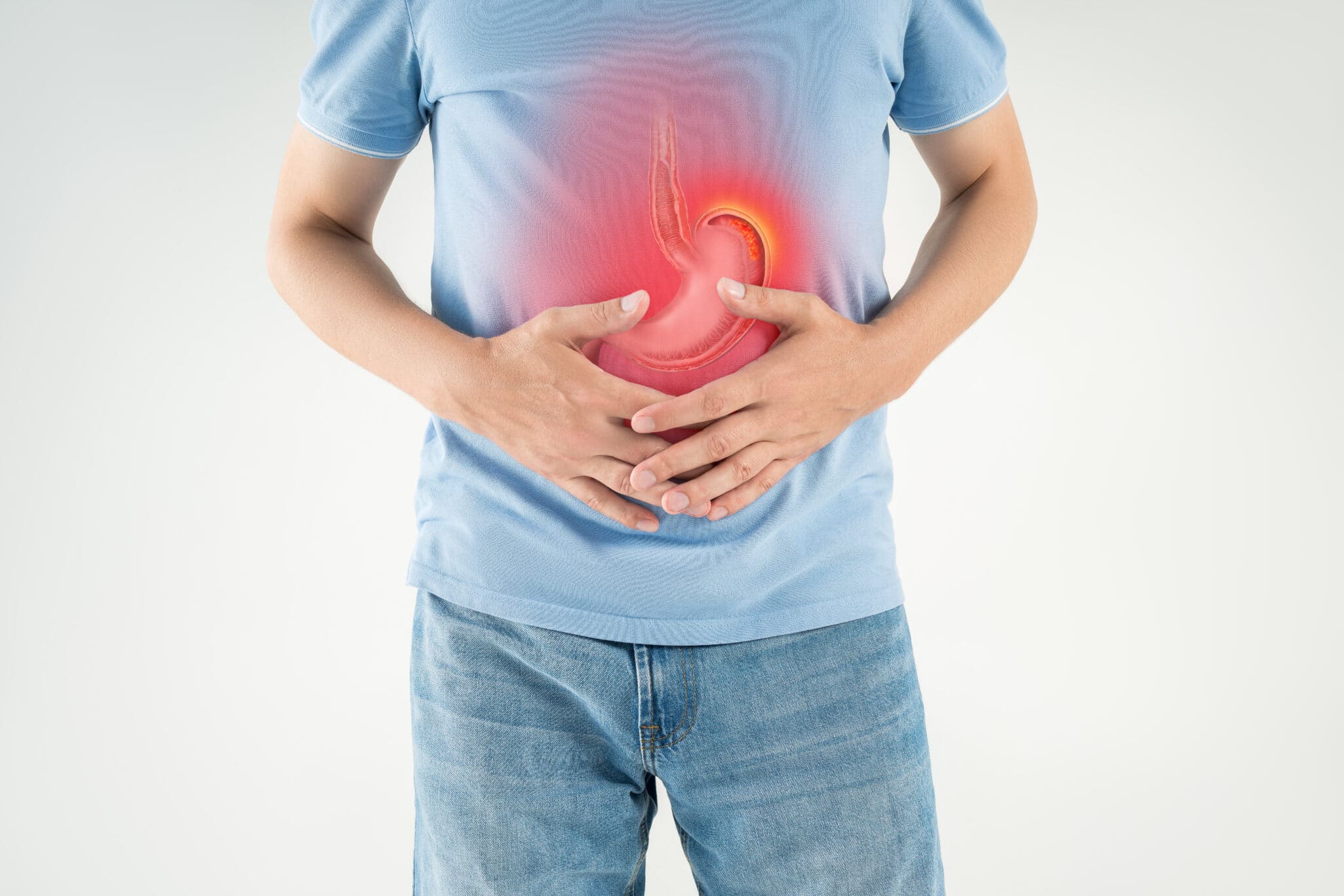 This image shows a man holding his stomach in visible discomfort, symbolizing one of the common symptoms of pernicious anemia.