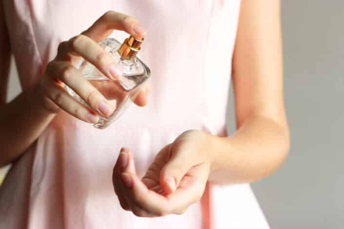 Woman spraying perfume on her wrist, representing exposure to phthalates that may affect gene expression